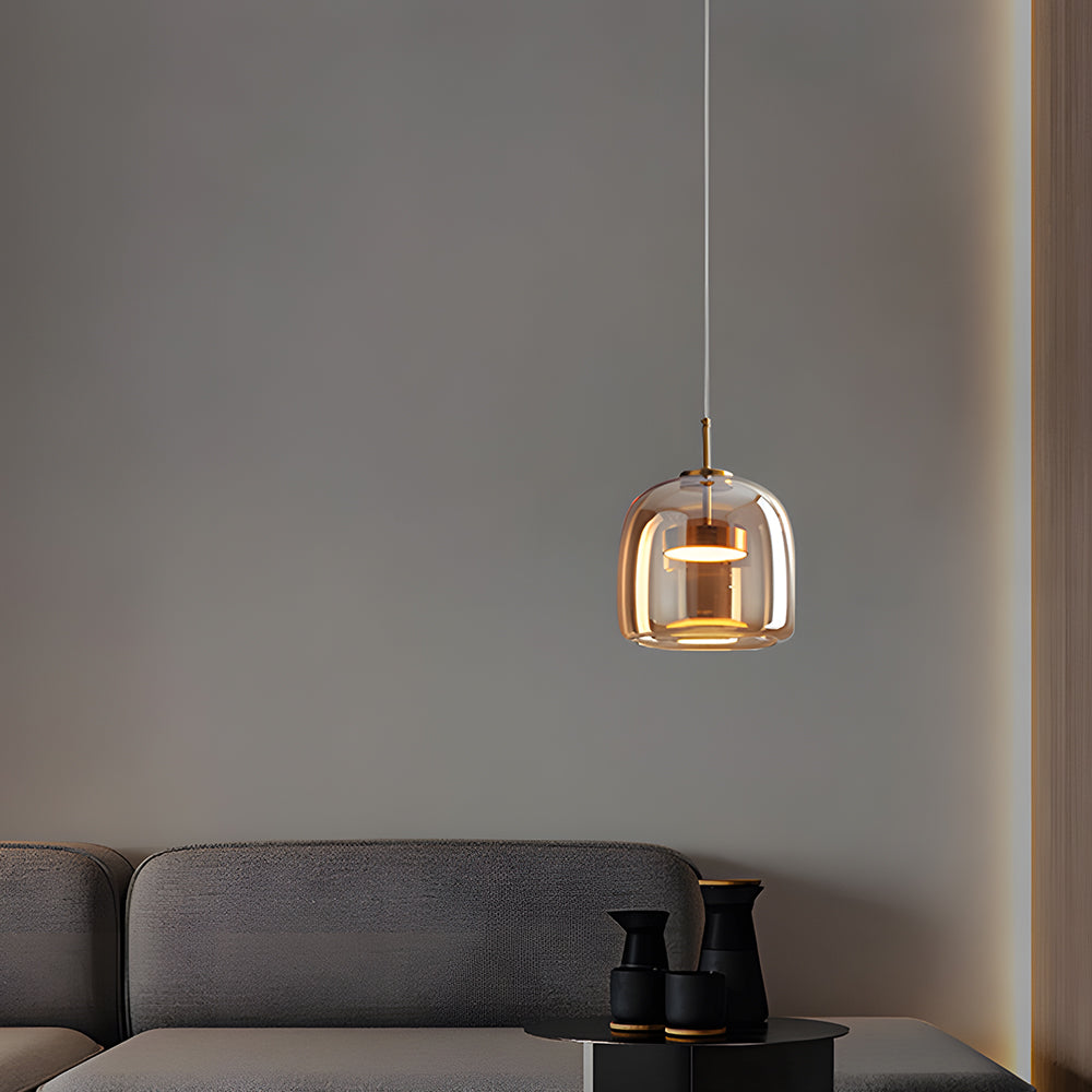 Nordic Glow A-shape amber smoked glass LED pendant light with warm glow, hanging in a contemporary room above a dark grey sofa and side table, highlighting its minimalist design.