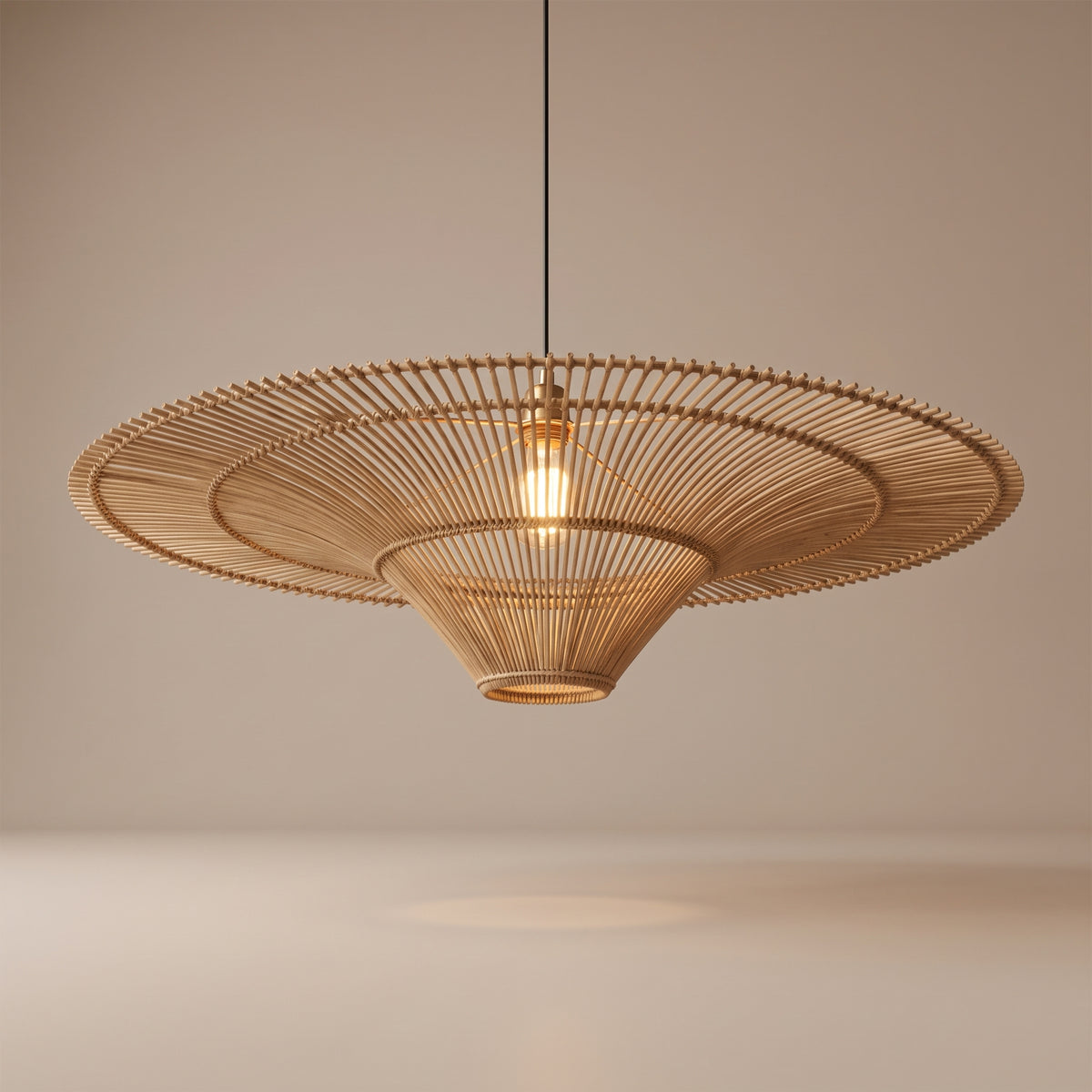 Handwoven oversized flat wicker pendant lamp shade lit with a warm glow on a beige studio background