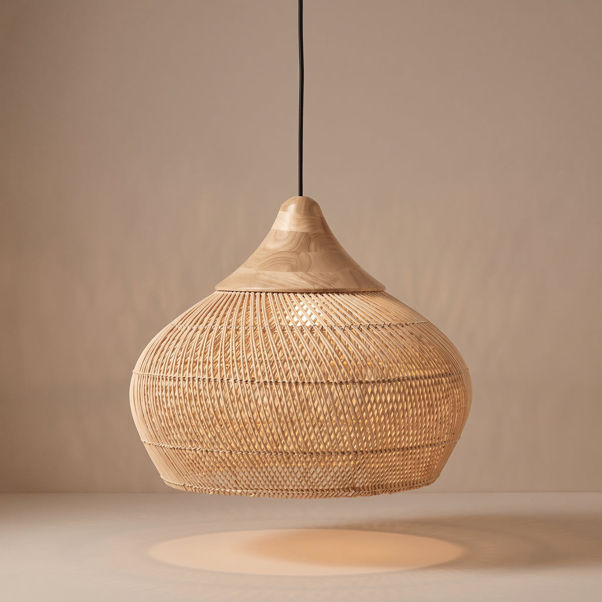 Handwoven wicker gourd pendant lamp shade with wood crown lit with a warm glow on a beige studio background