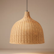 Handwoven wicker bell pendant lamp shade lit with a warm glow on a beige studio background