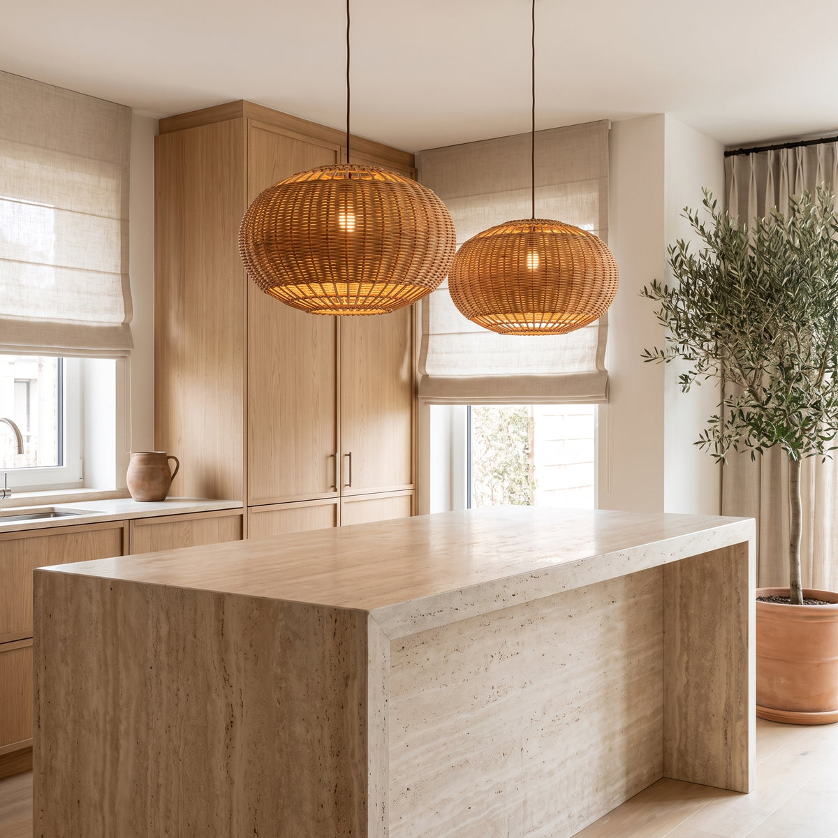 Wide wicker globe pendant lamp shade above a travertine kitchen island