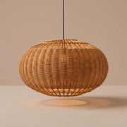 Handwoven wide wicker globe pendant lamp shade lit with a warm glow on a beige studio background