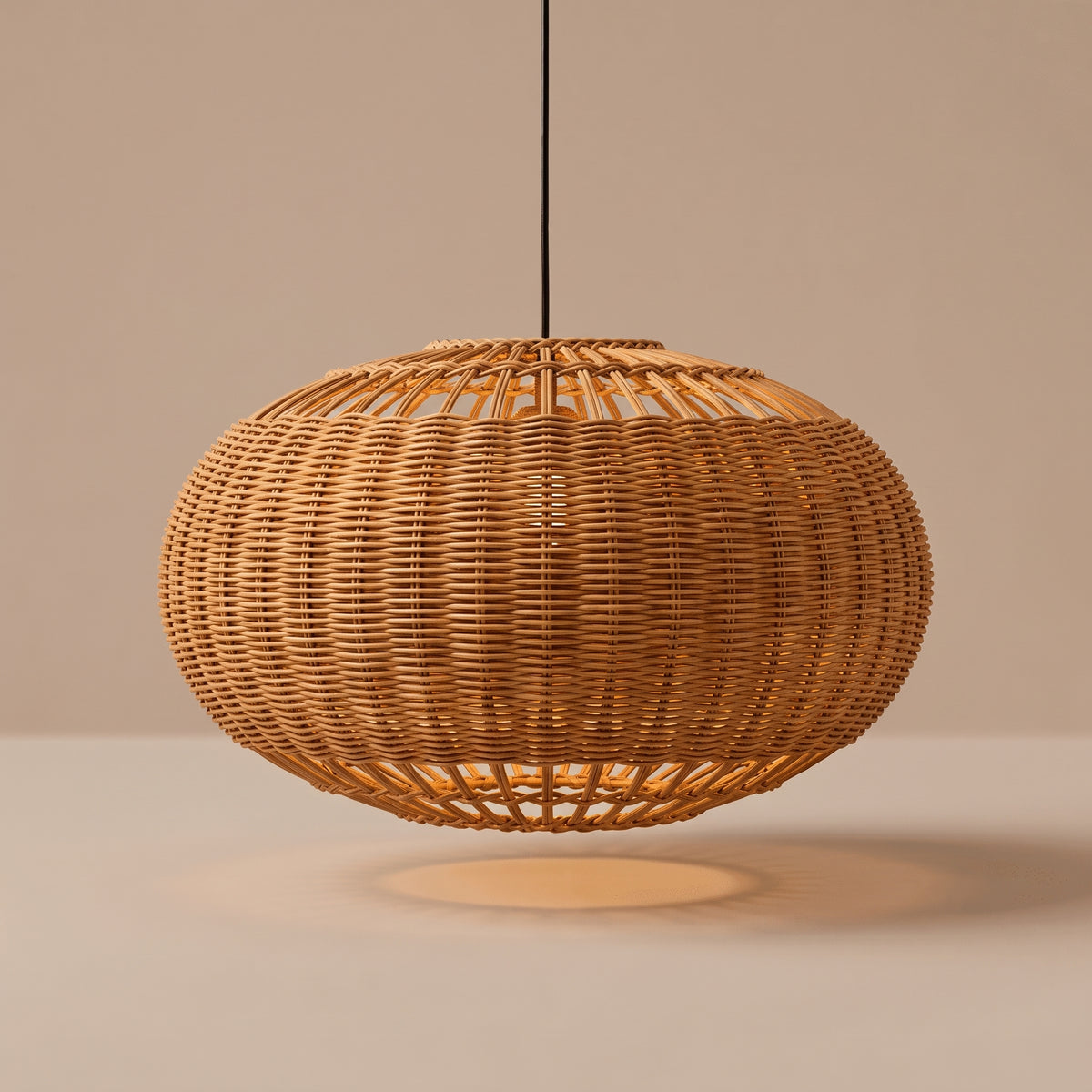 Handwoven wide wicker globe pendant lamp shade lit with a warm glow on a beige studio background