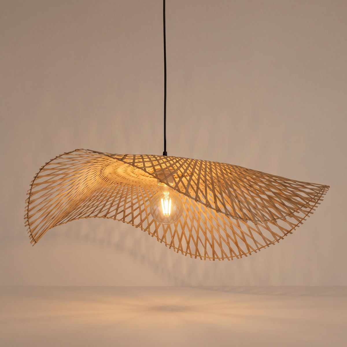Handwoven bamboo cone pendant lamp shade lit with a warm glow on a beige studio background