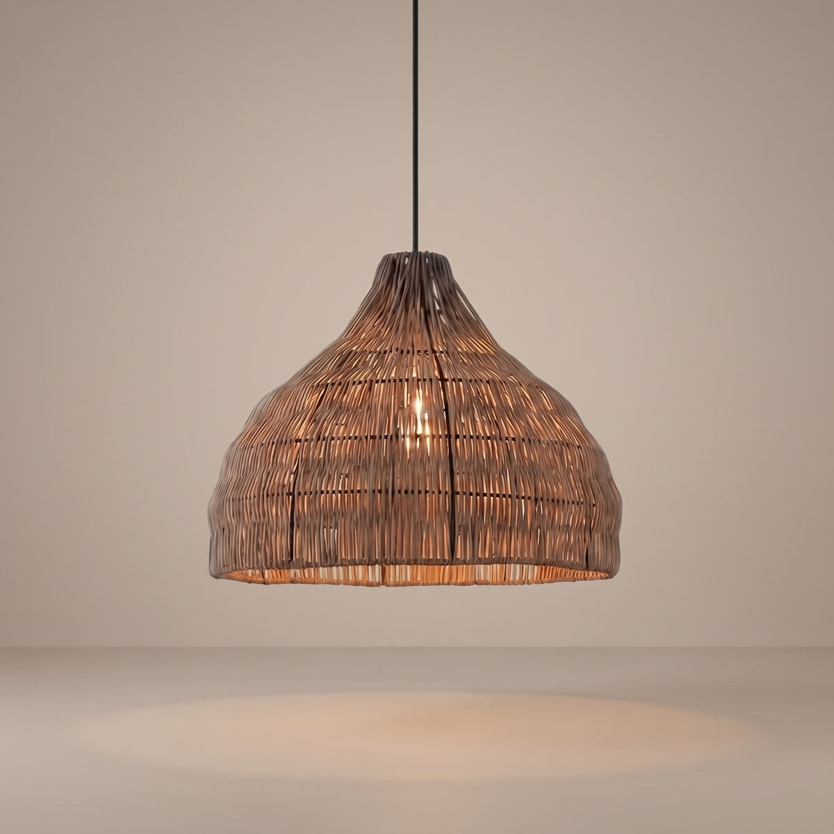 Handwoven weathered wicker pendant lamp shade lit with a warm glow on a beige studio background
