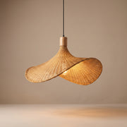 Handwoven asymmetric wicker pendant lamp shade lit with a warm glow on a beige studio background