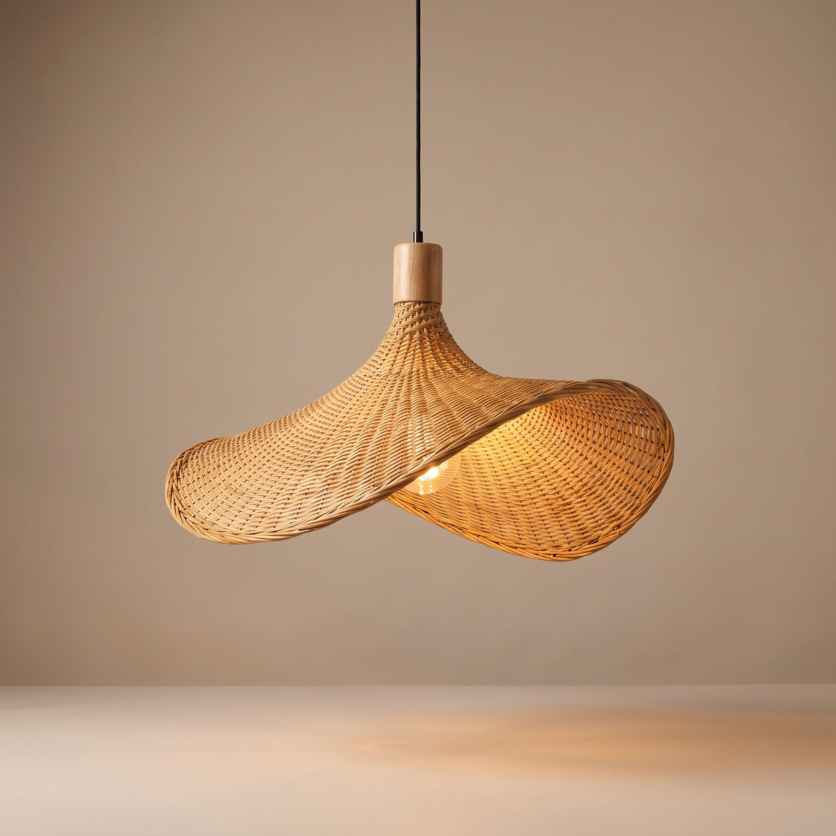 Handwoven asymmetric wicker pendant lamp shade lit with a warm glow on a beige studio background