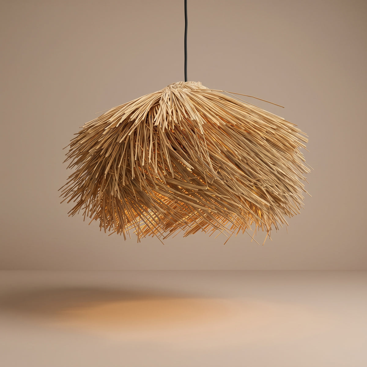 Handwoven straw fringe pendant lamp shade lit with a warm glow on a beige studio background