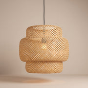 Handwoven layered bamboo pendant lamp shade lit with a warm glow on a beige studio background