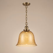 Ambra amber textured glass pendant with brass hardware, lit, studio view