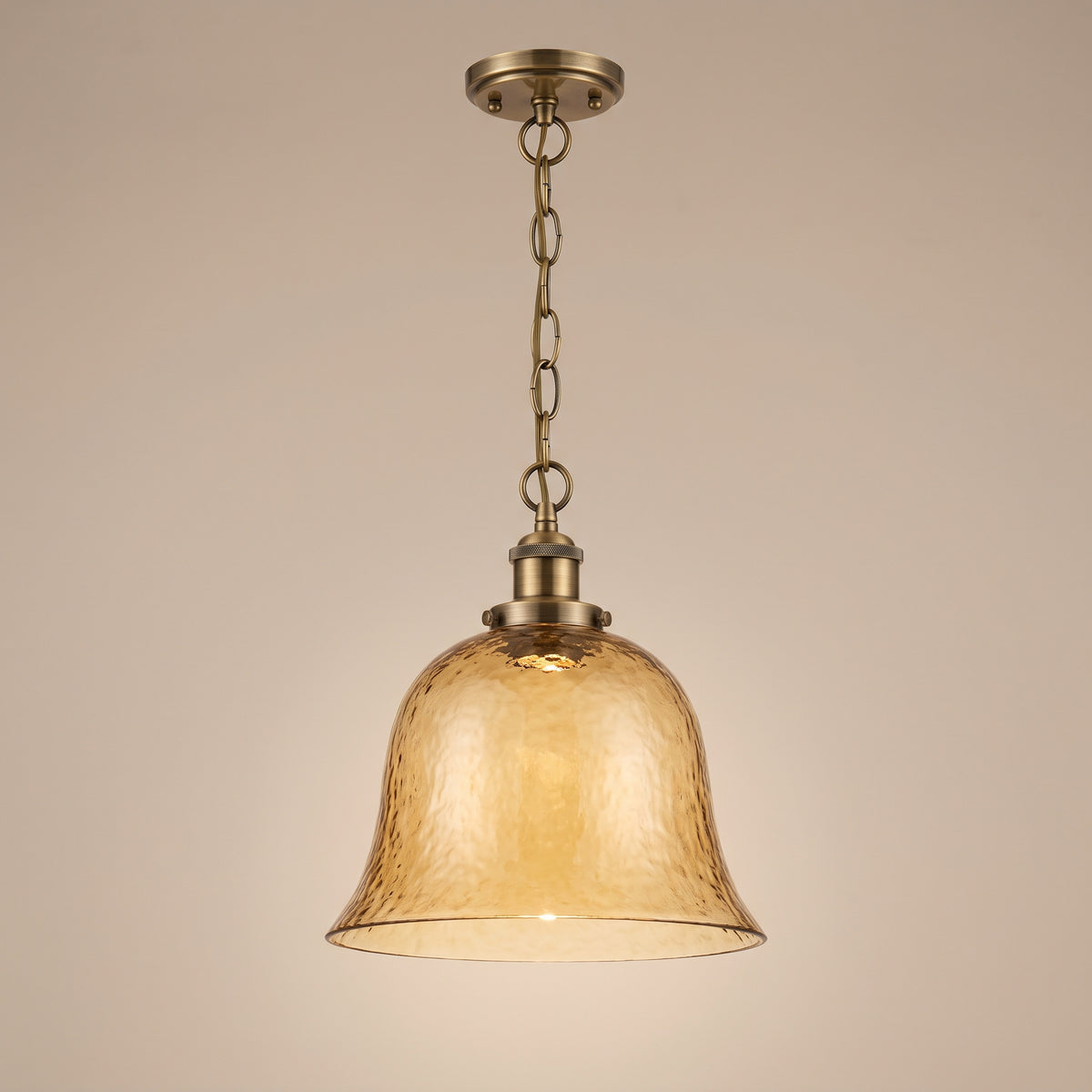 Ambra amber textured glass pendant with brass hardware, lit, studio view