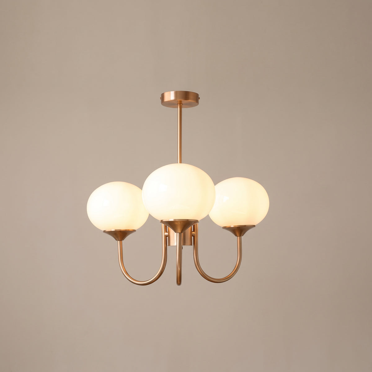 Bonbon chandelier with white glass globes and copper arms, lit, studio view