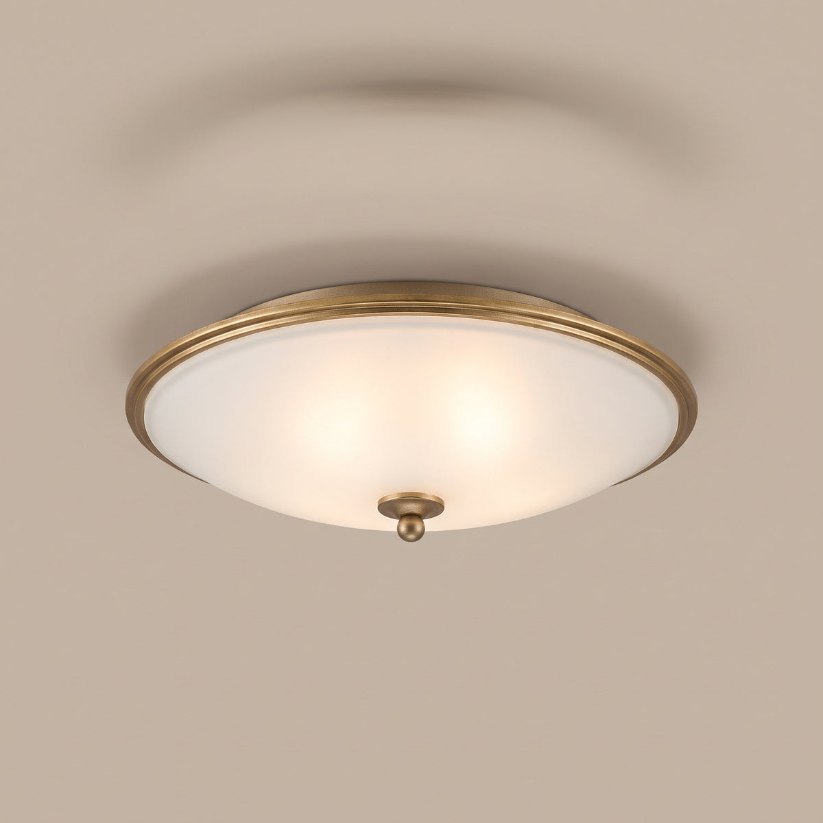 Orren pot-lid style frosted glass flush mount with gilded rim, lit, studio view