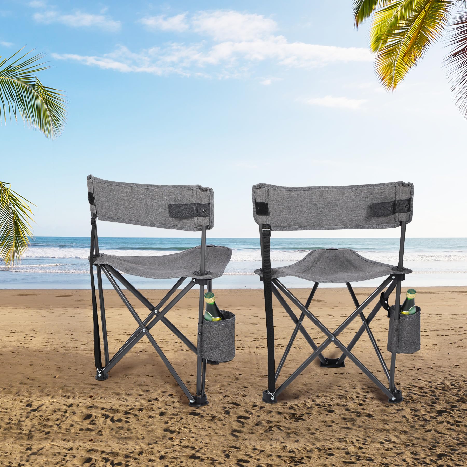 Two gray Alpine Retreat lightweight camping chairs with cup holders, each holding a bottle, set on a sandy beach with the ocean and palm trees in the background under a blue sky.