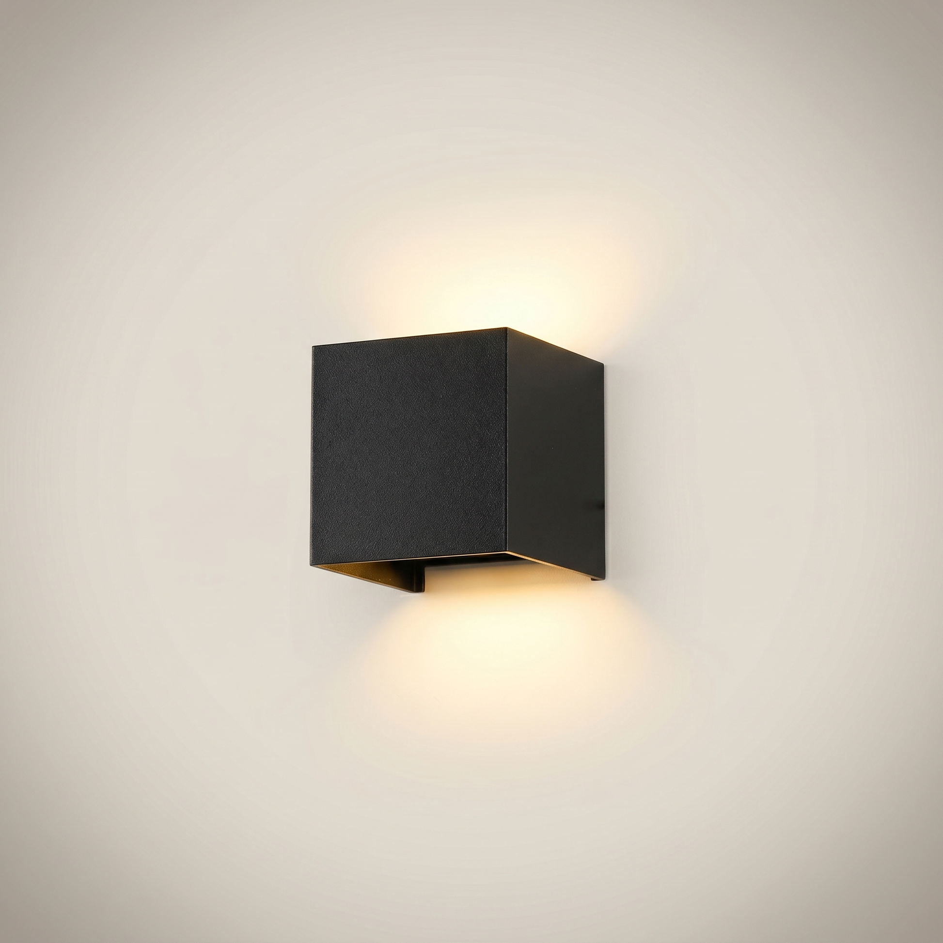 Front view of black aluminum square outdoor wall sconce lit with dimmable warm white beam adjusted to downward spread