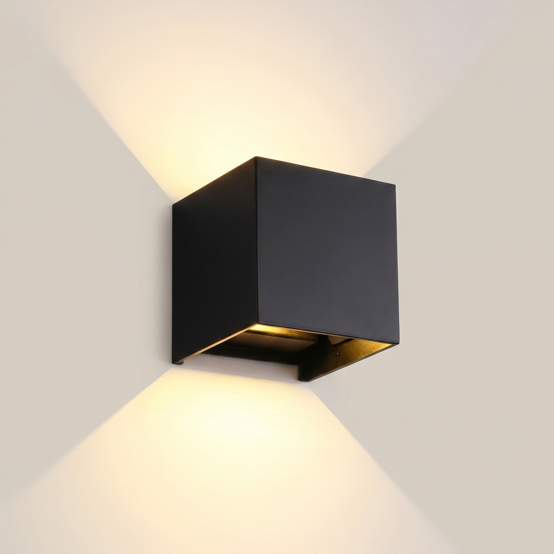 Black aluminum square outdoor wall sconce shown front view lit in ambient room lighting with adjustable light angle visible