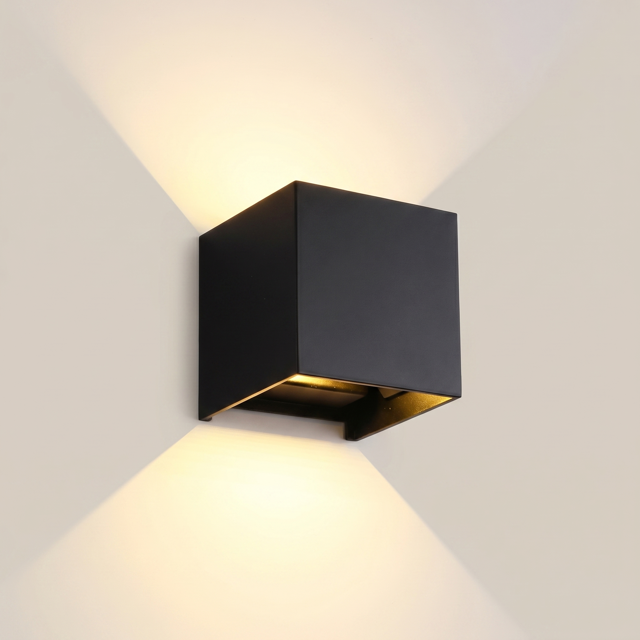 Black aluminum square outdoor wall sconce shown front view lit in ambient room lighting with adjustable light angle visible