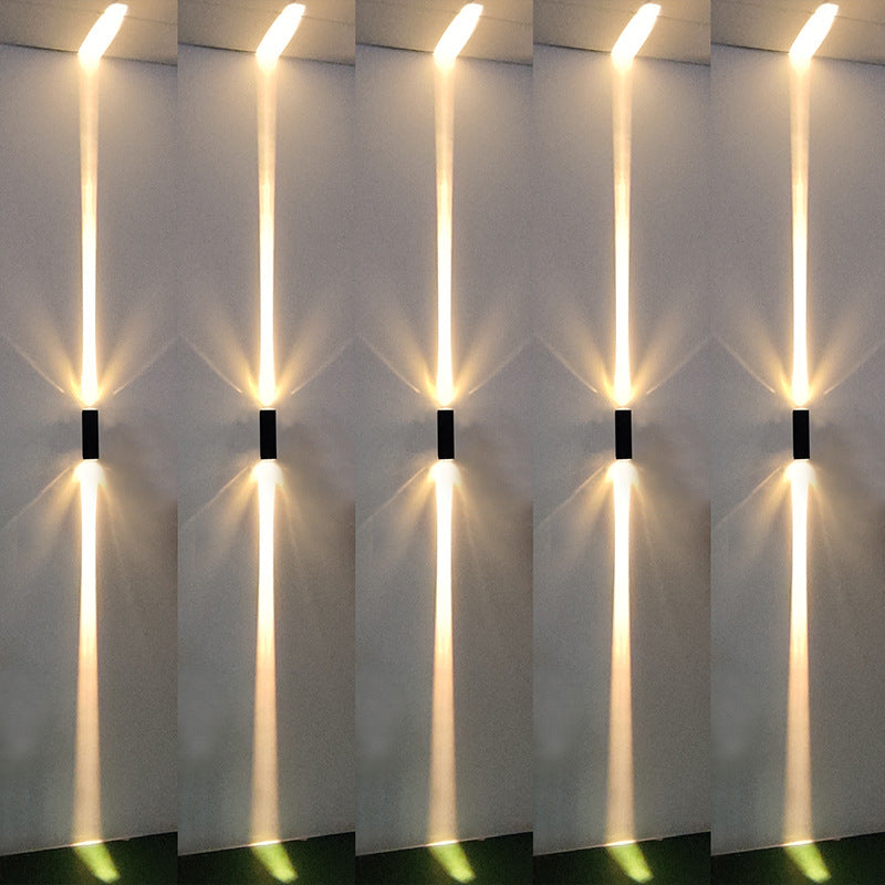 Ambient room view of black aluminum three-beam LED wall sconce with warm light installed on stairway with black shell finish