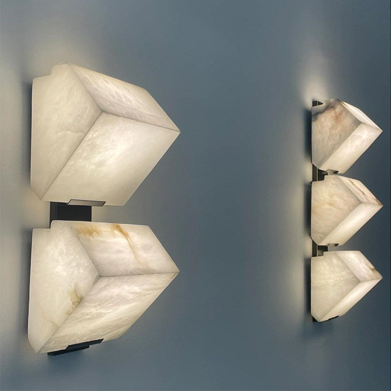 Three-quarter angle of black faux marble resin single-head LED wall sconce unlit with black iron body and visible faux marble shade texture