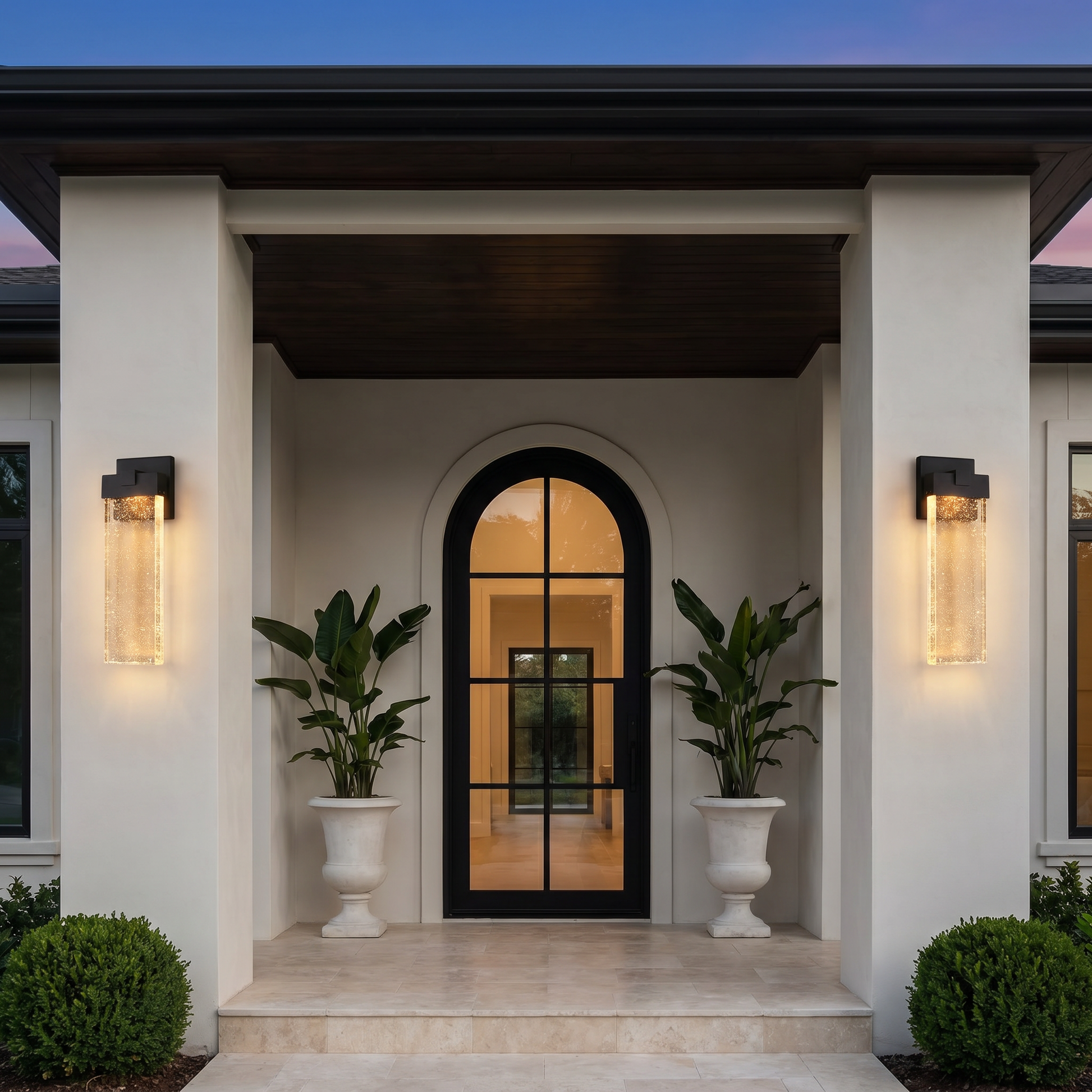 Three-quarter angle of black matte die-cast aluminum crystal COB LED outdoor wall sconce mounted on arched entry with warm glow