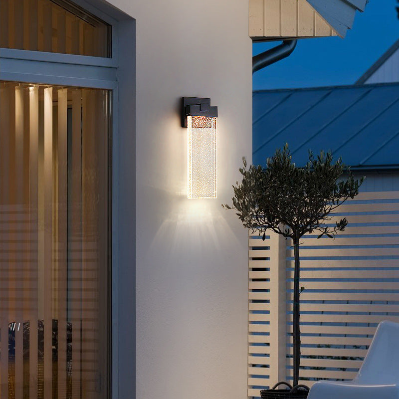 Three-quarter view of medium size black matte die-cast aluminum crystal COB LED outdoor wall sconce showing crystal texture and warm light