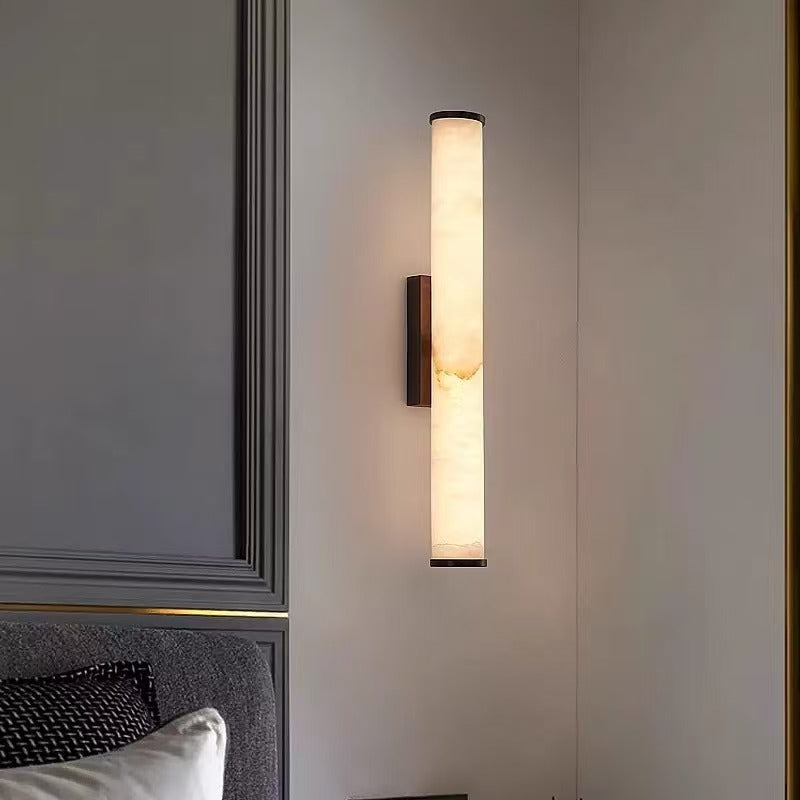 Side profile of Cloud Stone Resin Cylindrical Matte Black 14W LED wall sconce lit with warm light highlighting natural texture
