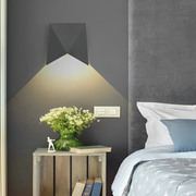 Creative Geometric LED Wall Sconce in bedroom with a nightstand.