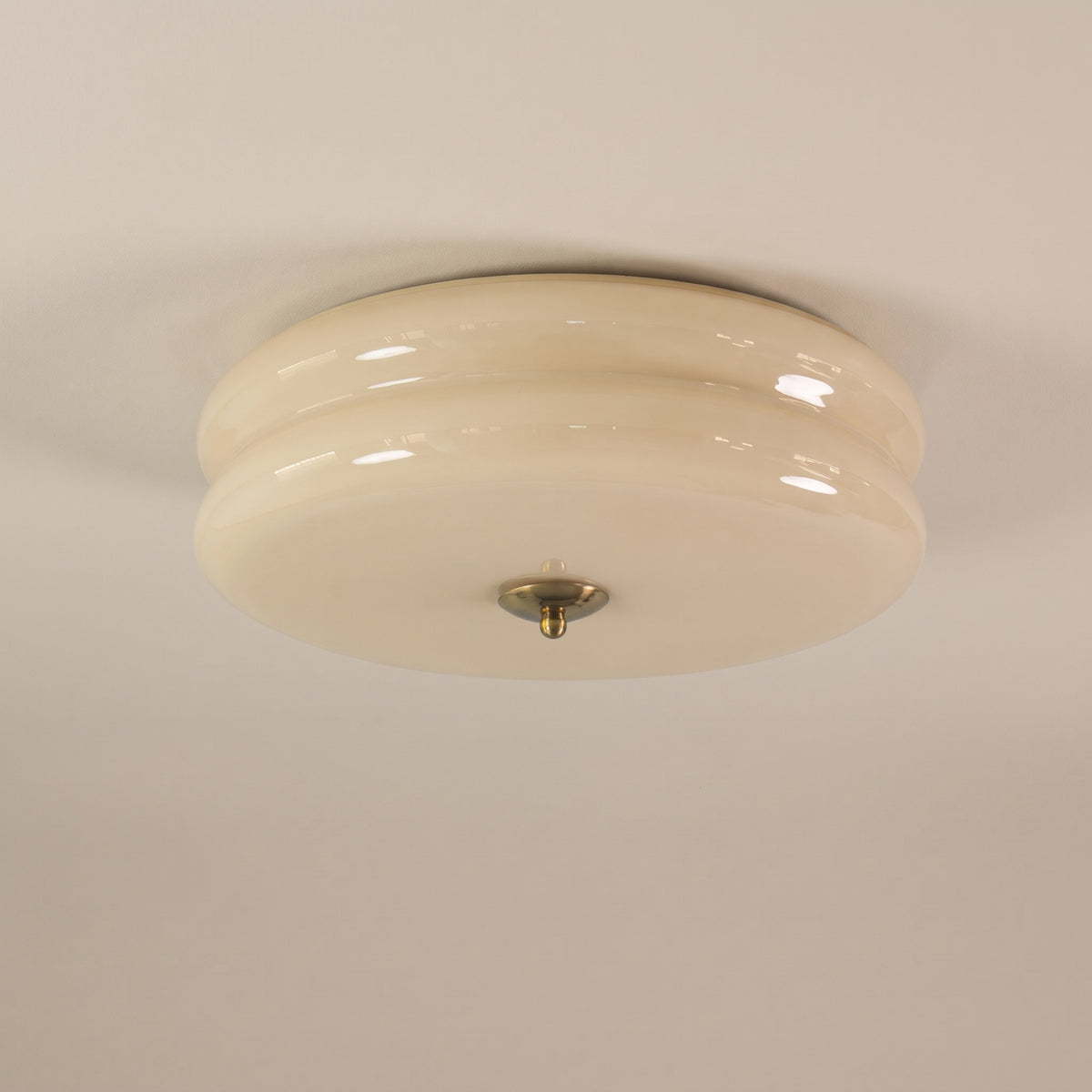 Époque glass pendant lamp with beige glass shade and brass finish accent, isolated on a black background.