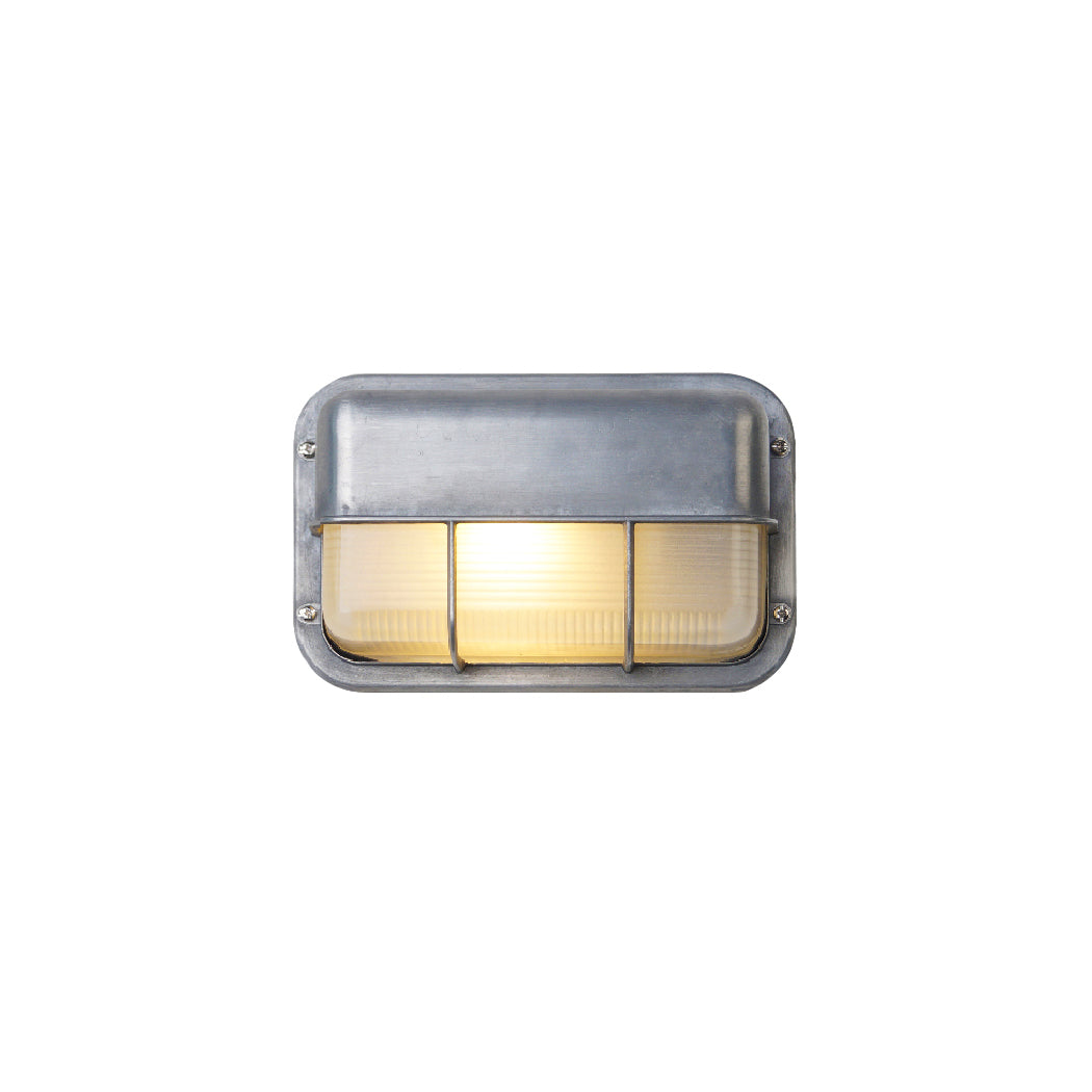 Fenwick vintage outdoor wall sconce, silver rectangular metal frame with clear ribbed glass diffuser and protective cage, illuminated on a white background.