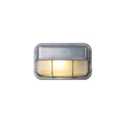 Fenwick vintage outdoor wall sconce, silver rectangular metal frame with clear ribbed glass diffuser and protective cage, illuminated on a white background.
