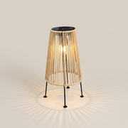 Handwoven rattan geometric solar LED tripod outdoor lantern shown front view in natural tan with warm light and tripod base visible