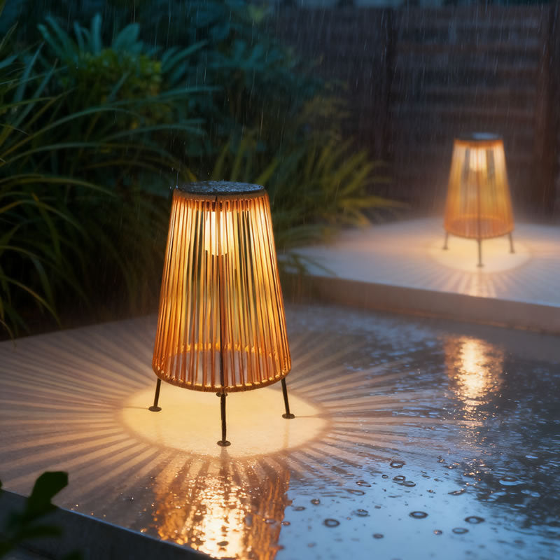 Side profile of handwoven rattan geometric solar LED tripod outdoor lantern in natural tan with warm light and USB charging port visible