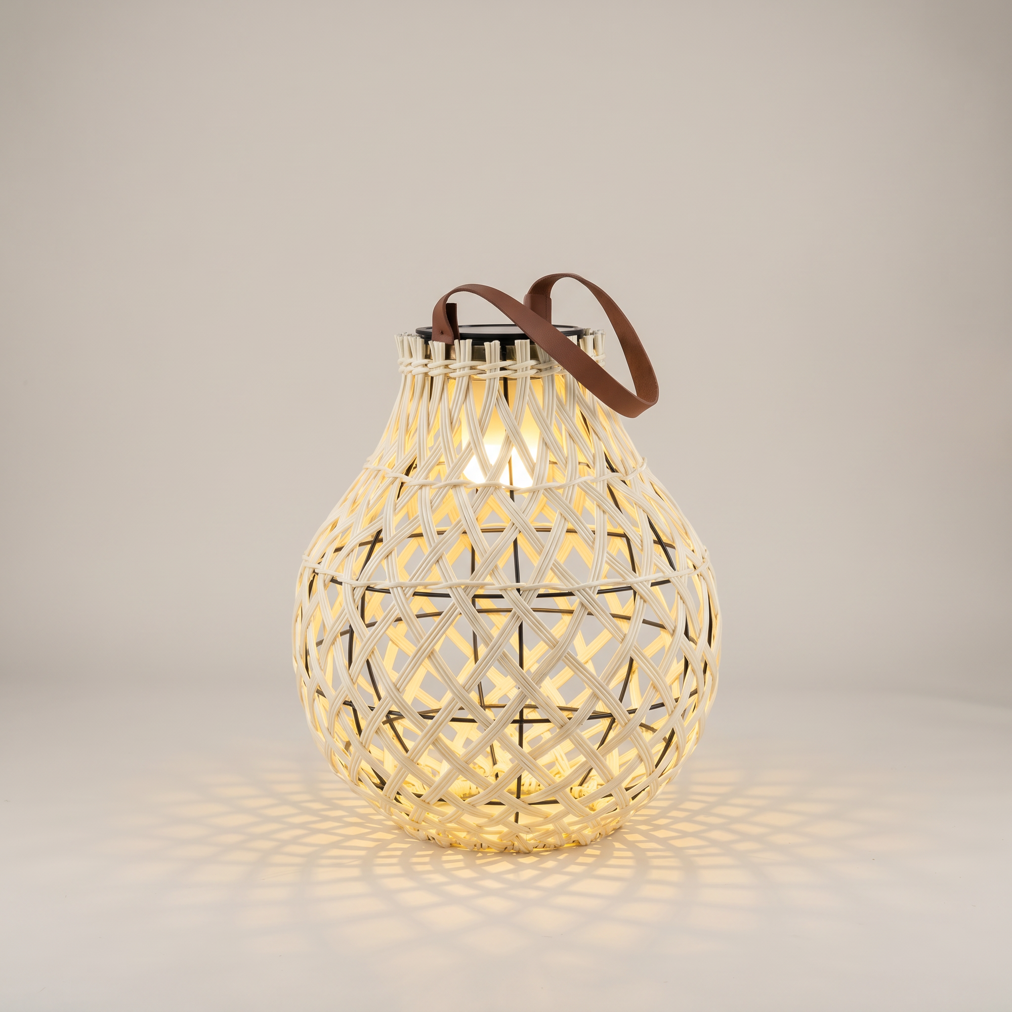 Top-down view of handwoven rattan geometric solar LED tripod outdoor lantern in natural tan showing solar panel and rattan weave