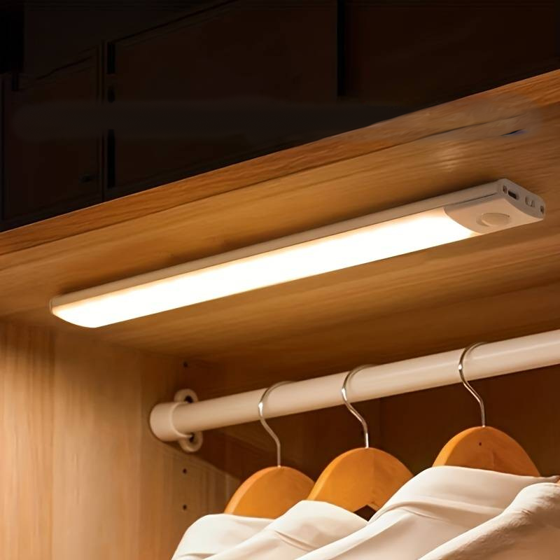 White Lumos Glow motion sensor light installed inside a wooden wardrobe, providing bright automatic LED lighting for easy visibility of clothes. This wireless, energy-efficient light is an ideal smart lighting solution for closets and home safety.