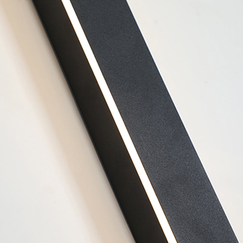 A close-up view of the Luna Edge IP65 linear LED wall light, featuring a black metal finish and an illuminated white light strip, mounted on a white wall. Highlights the sleek design and bright illumination.