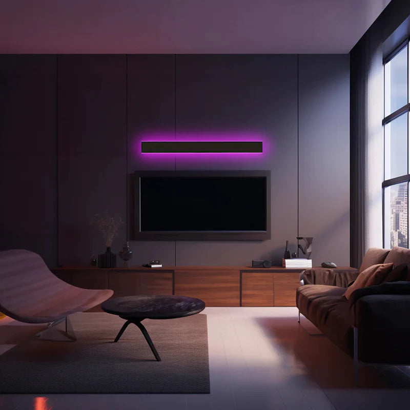 Luna Edge IP65 Linear LED Wall Light in black metal with acrylic finish, displaying a single horizontal RGB light emitting a purple glow above a television in a modern living room. Highlights the versatile aesthetic of this linear LED fixture.