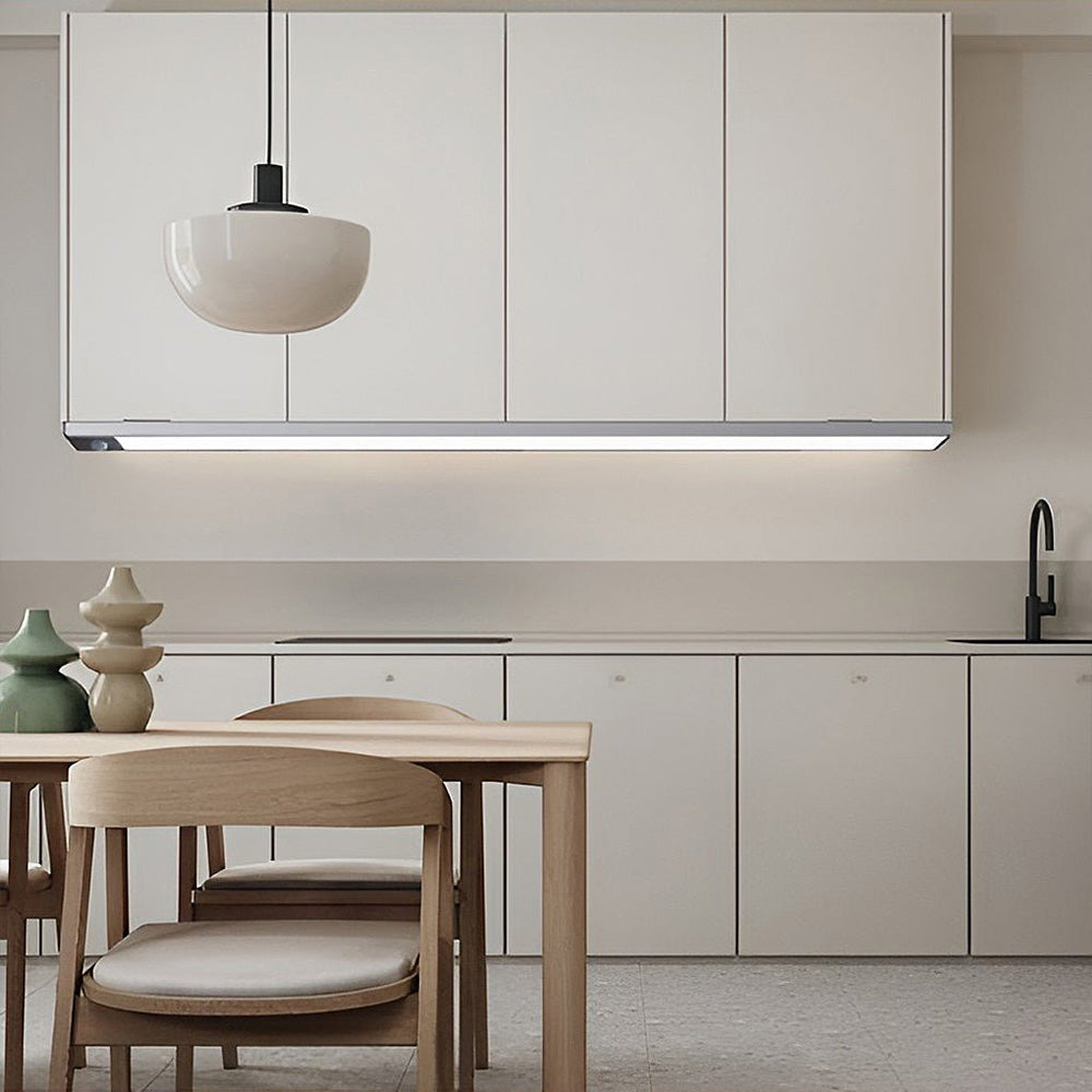 Luna Glow LED under cabinet wall light in silver installed under white kitchen cabinets, illuminating a modern kitchen counter.