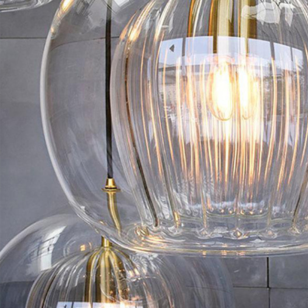 Close-up view of multiple Lustre Aura LED pendant lights in clear glass, highlighting the ribbed inner glass design and the warm glow of the light.