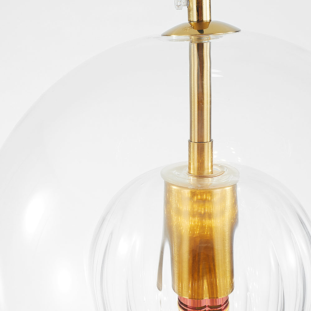 Close-up view of the Lustre Aura LED pendant light, showcasing the clear amber glass shade, brass hardware, and the unique ribbed inner glass detail.