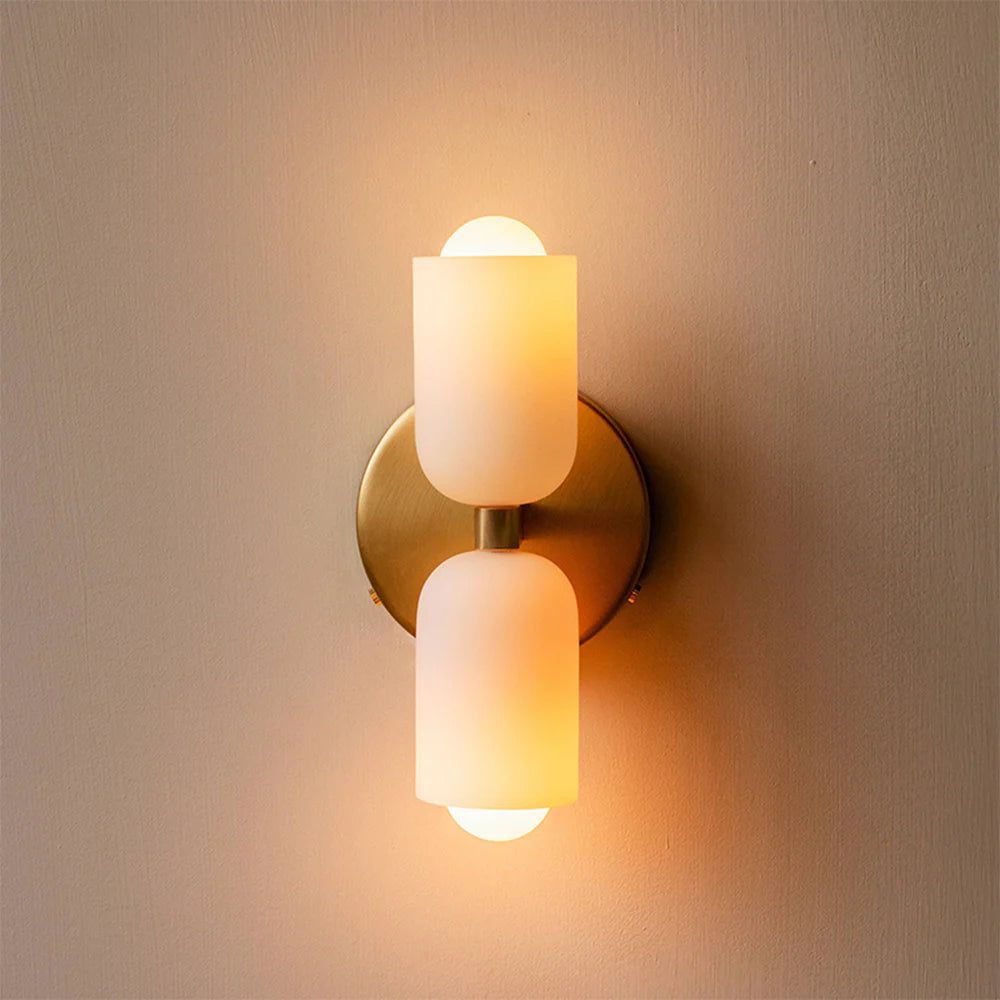 Luxe Parisian Glow LED wall sconce with gold iron finish and two frosted white glass shades, illuminated with a warm glow, mounted on a light beige wall.
