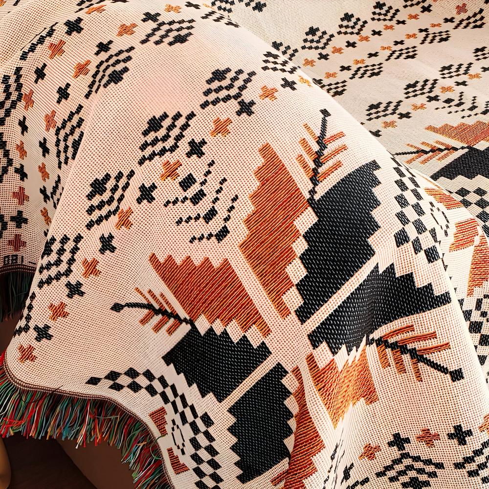 Close-up view of the Nomad Oasis picnic blanket, highlighting its intricate Moroccan boho pattern in orange, black, and white, along with the detailed fringe edge.