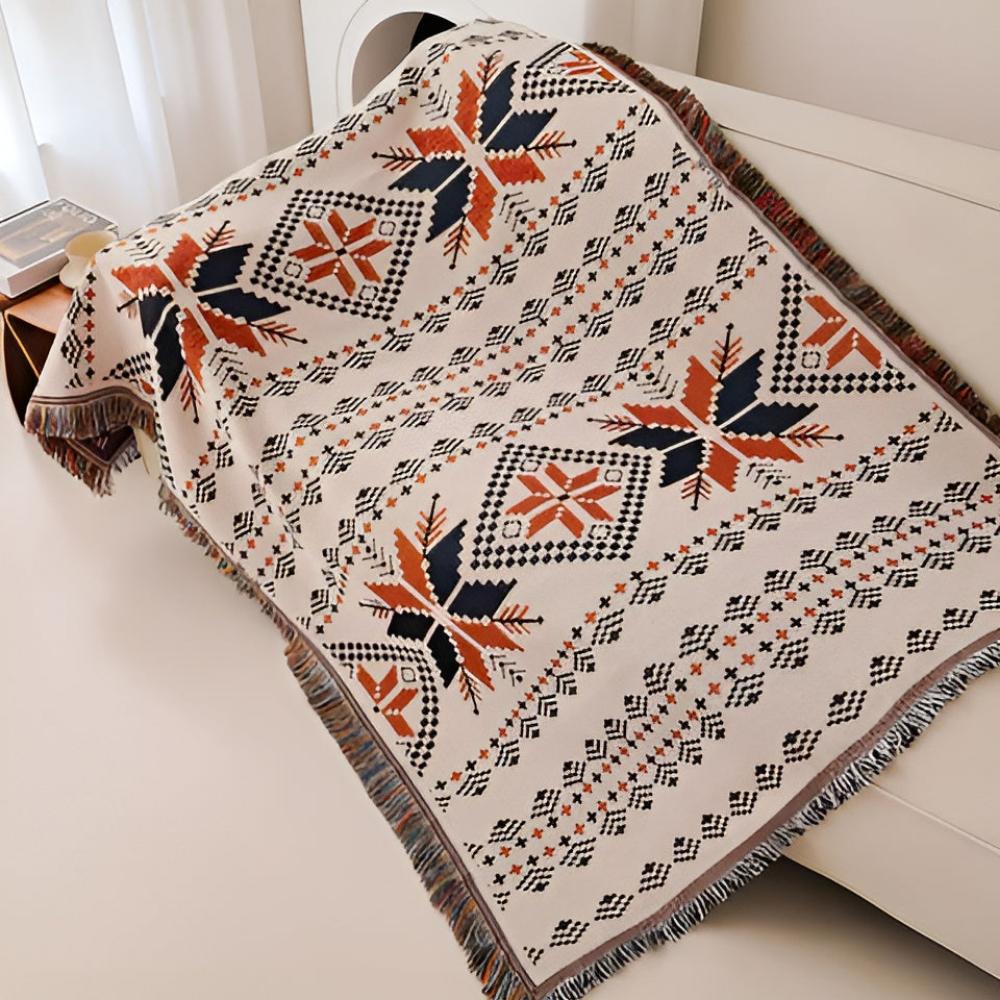 Nomad Oasis picnic blanket with Moroccan boho pattern draped over a white sofa, showcasing the full intricate design and vibrant colors, perfect for home decor.