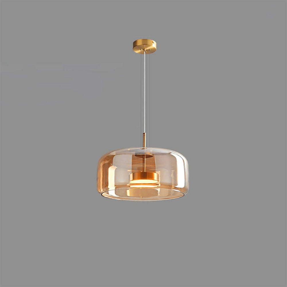 A single Nordic Glow smoked amber glass LED pendant light with a minimalist design, featuring a gold-colored canopy and internal fixture, illuminated with a warm light against a plain grey background.