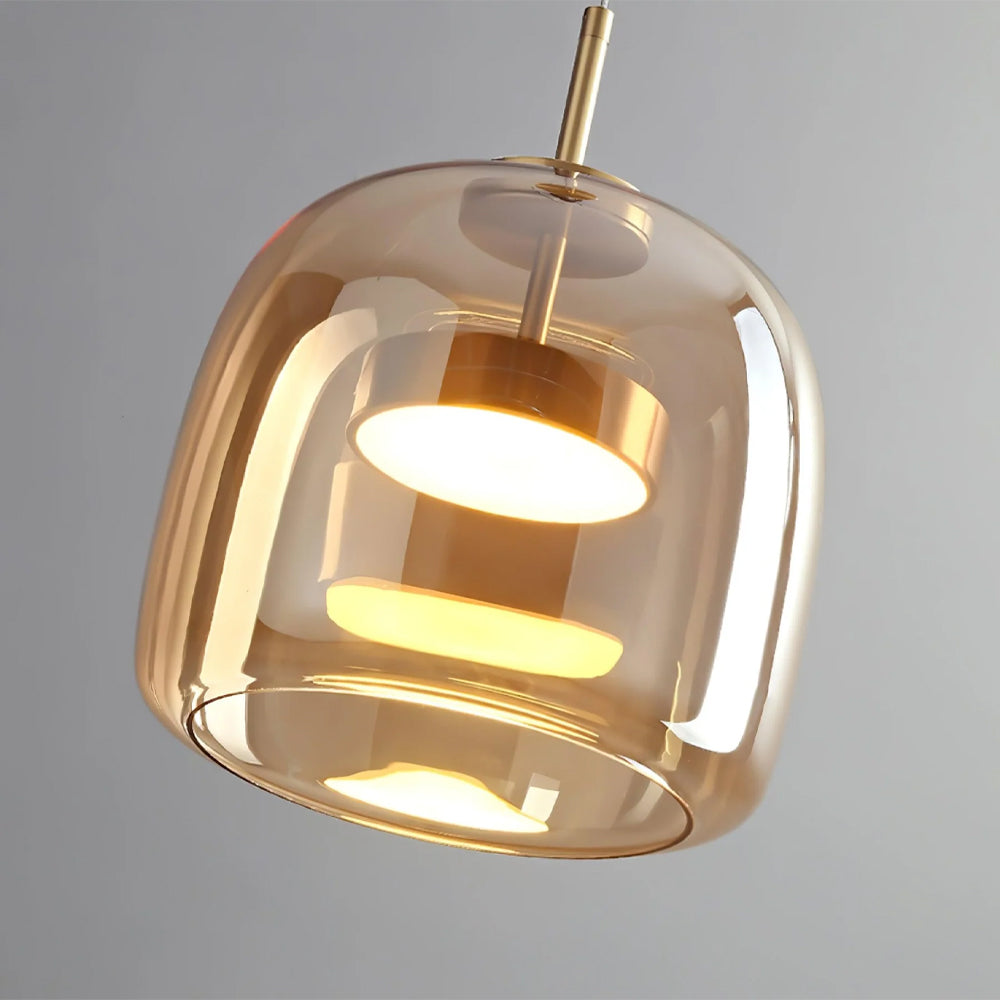 Close-up of the Nordic Glow smoked amber glass LED pendant light, showcasing its minimalist design, illuminated warm light, and brass-colored internal fixture.