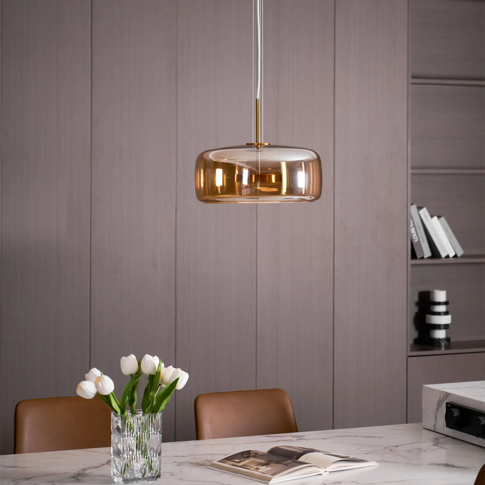 Nordic Glow smoked glass LED pendant light with minimalist design, featuring an illuminated amber glass shade, hanging in a modern dining room with a marble table and white tulips.