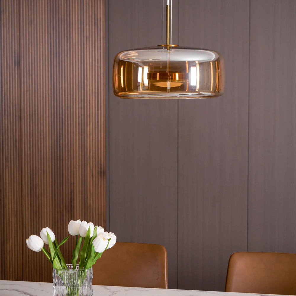 Close-up view of the Nordic Glow smoked glass LED pendant light with minimalist design, showing its amber glass shade illuminated with a warm glow in a modern dining room.