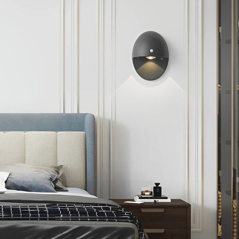 Oval Shape Motion Sensor Wall Light Sconce on top of nightstand.