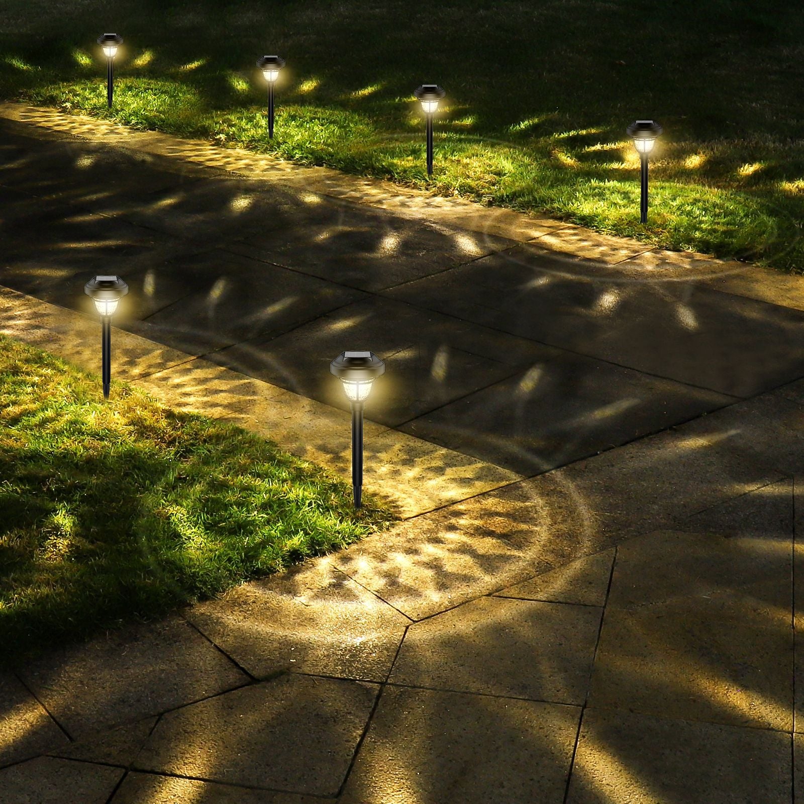 Three-quarter view of PP Round Solar Light Sensor glowing warm light on outdoor stone pathway