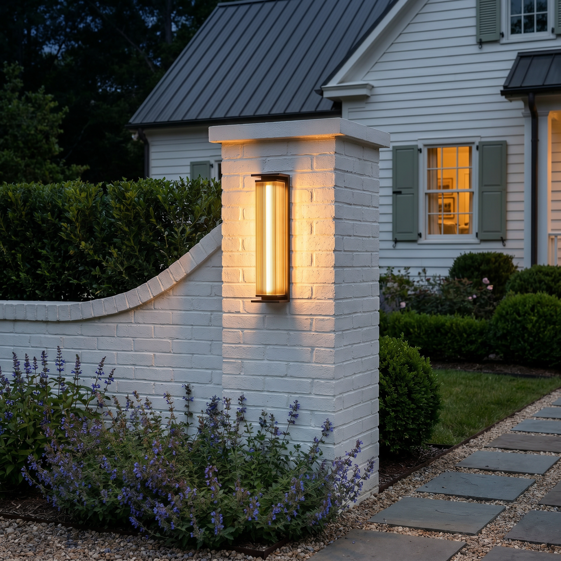 Stainless steel vertical ribbed LED outdoor wall sconce at three-quarter angle glowing warm light mounted on patio wall