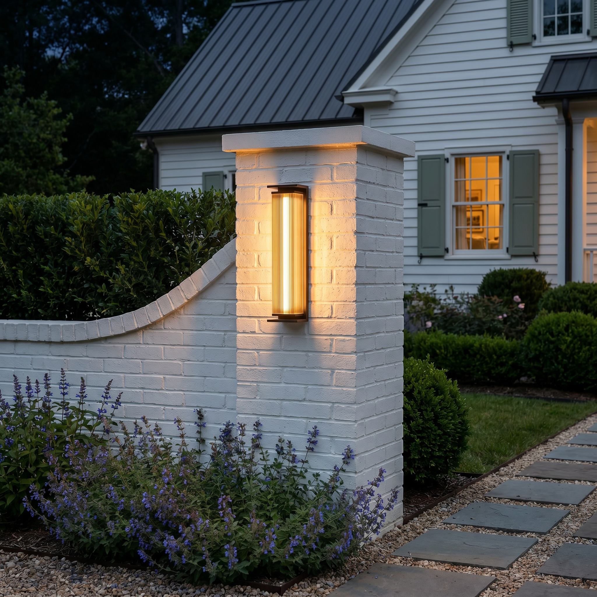 Stainless steel vertical ribbed LED outdoor wall sconce at three-quarter angle glowing warm light mounted on patio wall